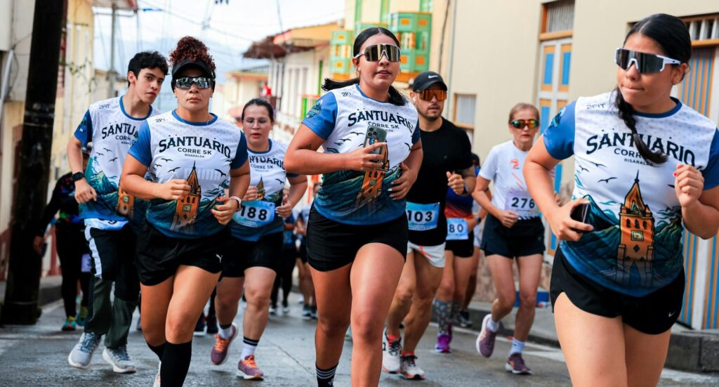 Participants in a vibrant street race wearing athletic wear and numbered bibs, running energetically.